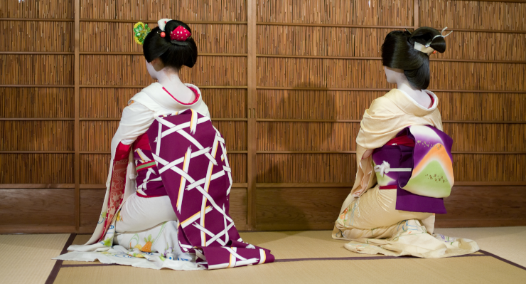 A maiko (senior) and geisha dancing, facing away from the audience and camera